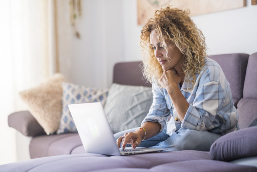 Smiling caucasian adult hipster sit relax on couch using modern laptop browsing internet